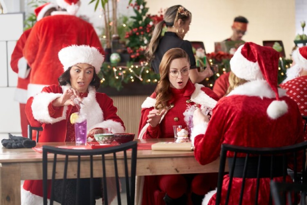 Girls in Santa Suits sitting at a table in a scene from The Santa Summit on Hallmark