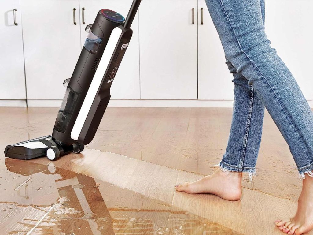 person using wet/dry vacuum to clean up spill on floor