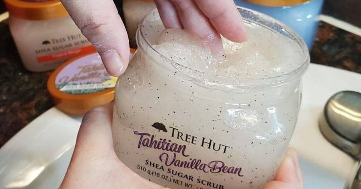 Hand dipping into a jar of Tree Hut Sugar Scrub