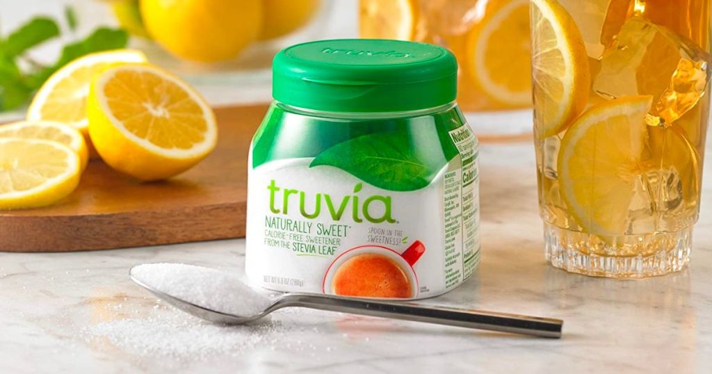Truvia 9 8oz with a spoon on a kitchen counter infront of a pitcher of iced tea with lemon