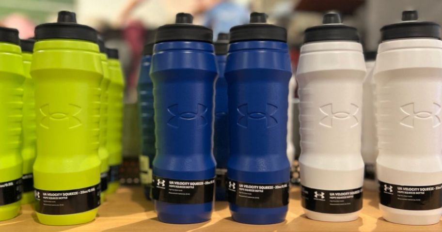 Under Armour Water Bottles on a shelf at a store in multiple colors