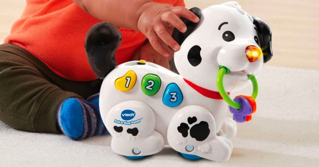 a baby playing with an VTech pull and sing puppy