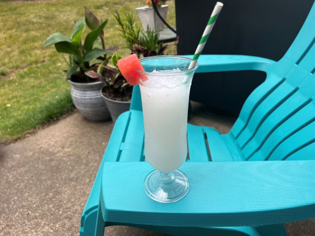 Cup with an iced drink and a straw sitting on a blue chair outside