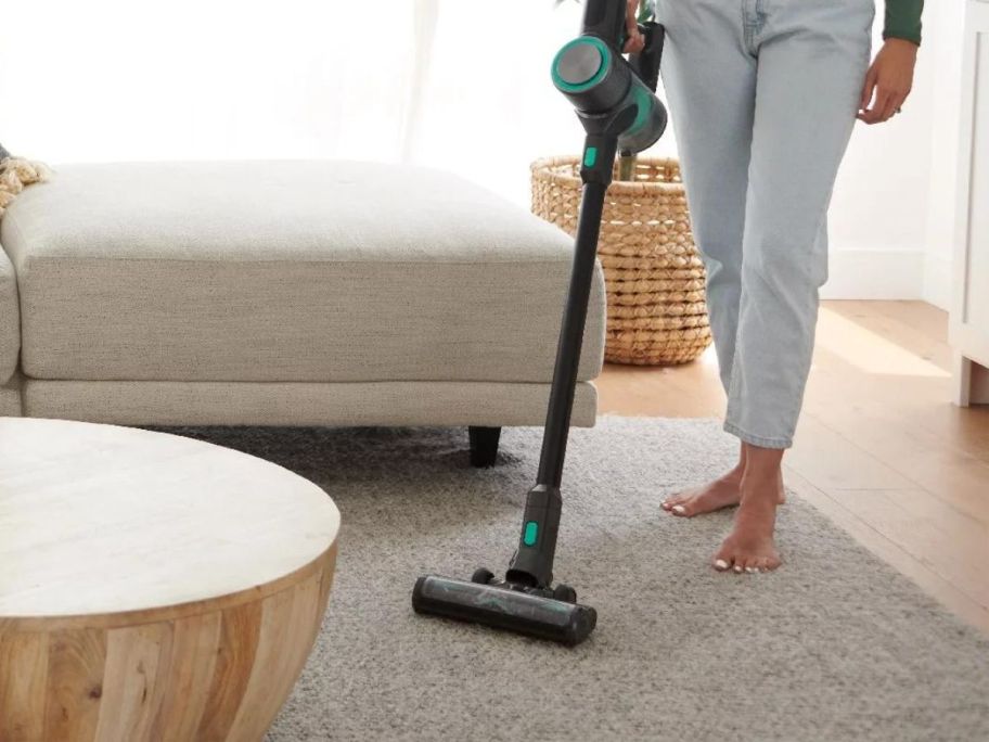 woman using Wyze Cordless Stick Vacuum on carpet in living room