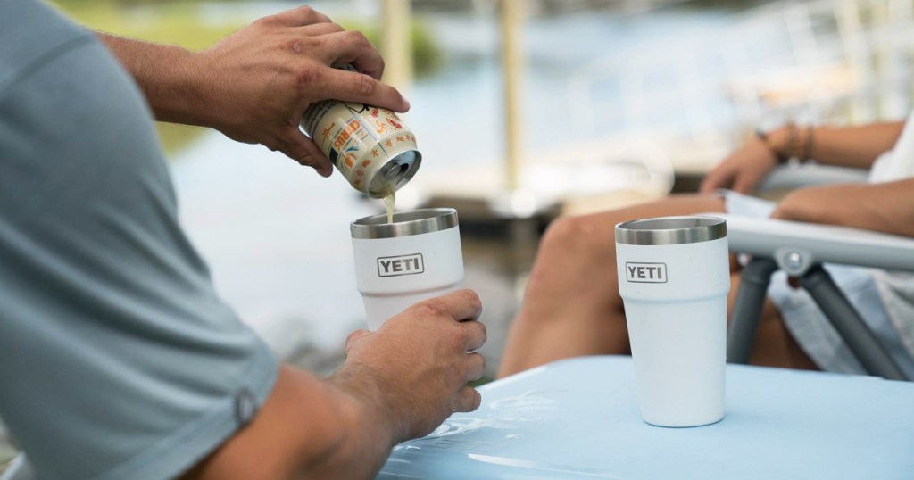 man pouring a canned drink into a white yeti pint cup