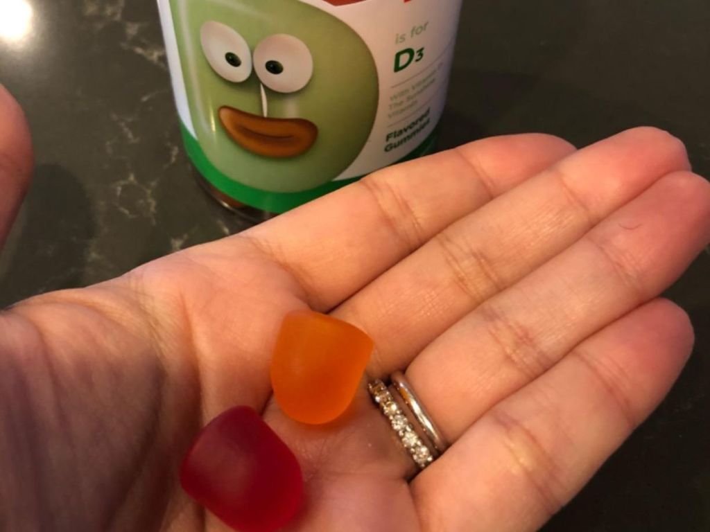 Zahler Chapter One Vitamin d# Gummies in a human hand next to a bottle of the gummies