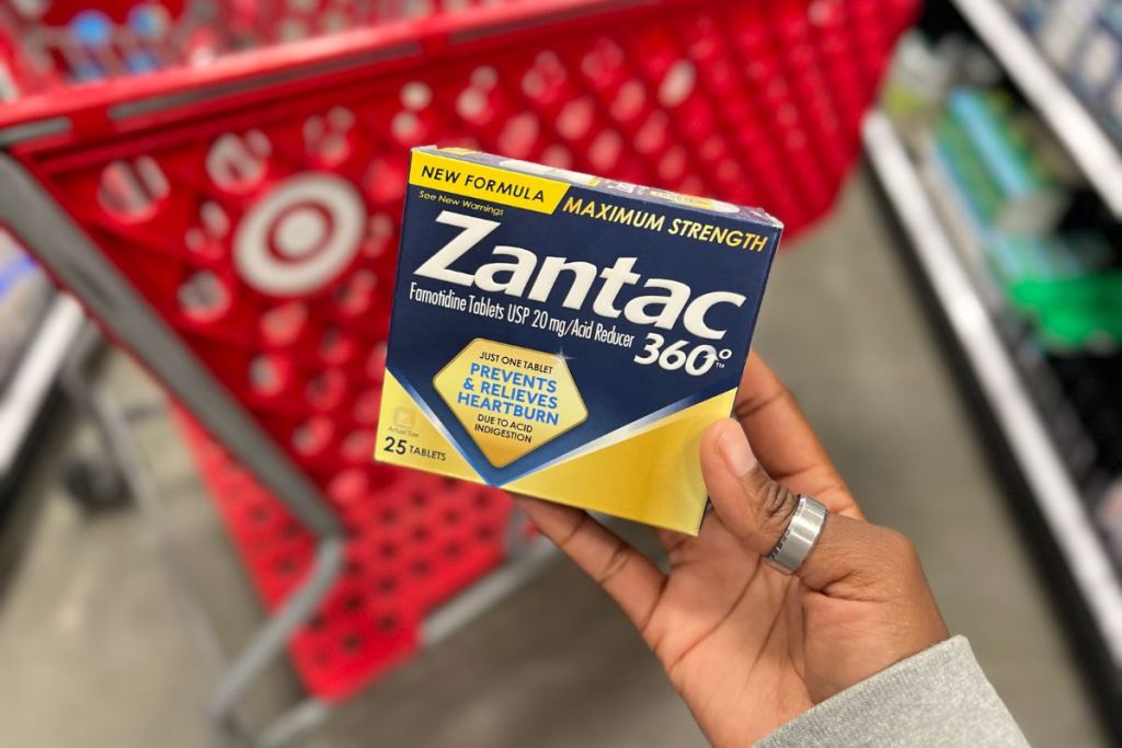 Zantac 360 Heartburn Prevention & Relief Tablets in woman's hand beside of a Target Shopping Cart