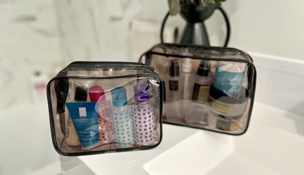 two translucent gray toiletry bags sitting on white sink in bathroom