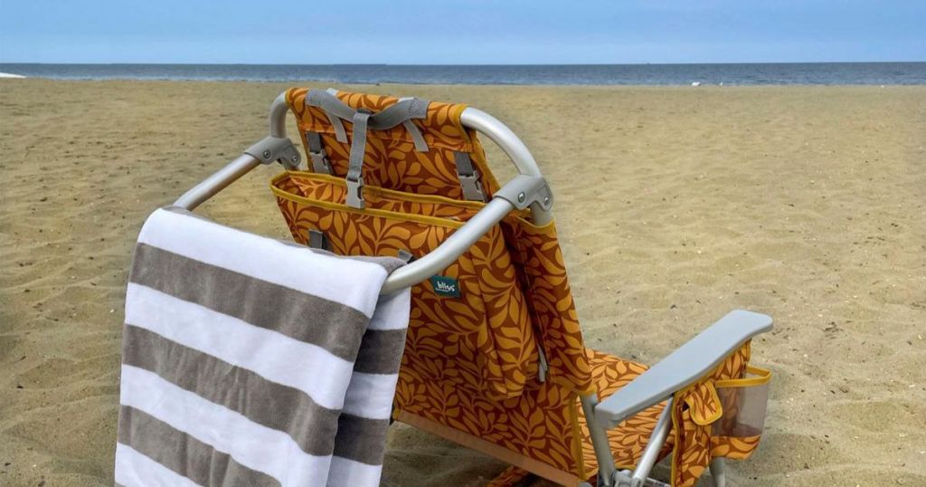 orange and brown leaf patterned beach chair with striped towel on towel rack on beach