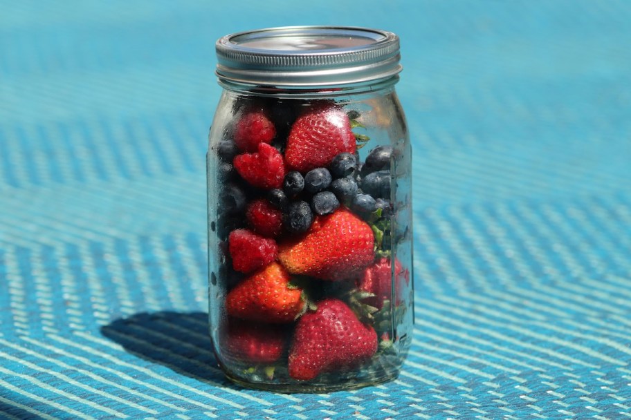 berries in mason jar sitting on blue table