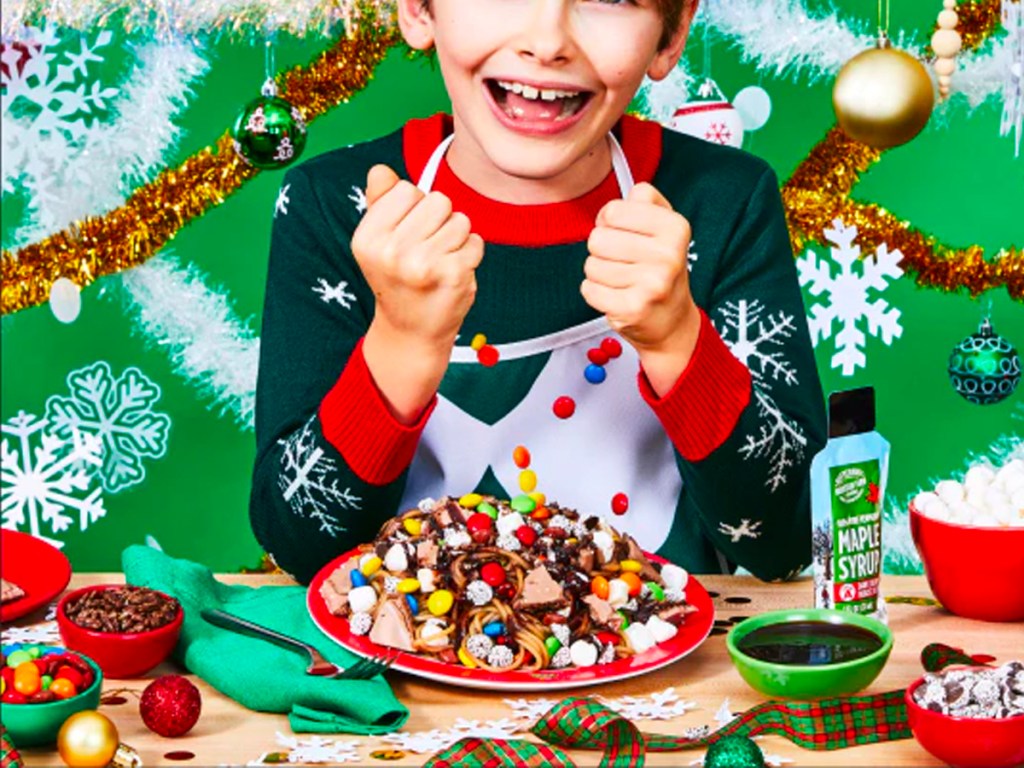 child wearing elf apron with plate full of spaghetti 