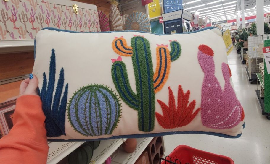 womans hand holding a cactus pillow