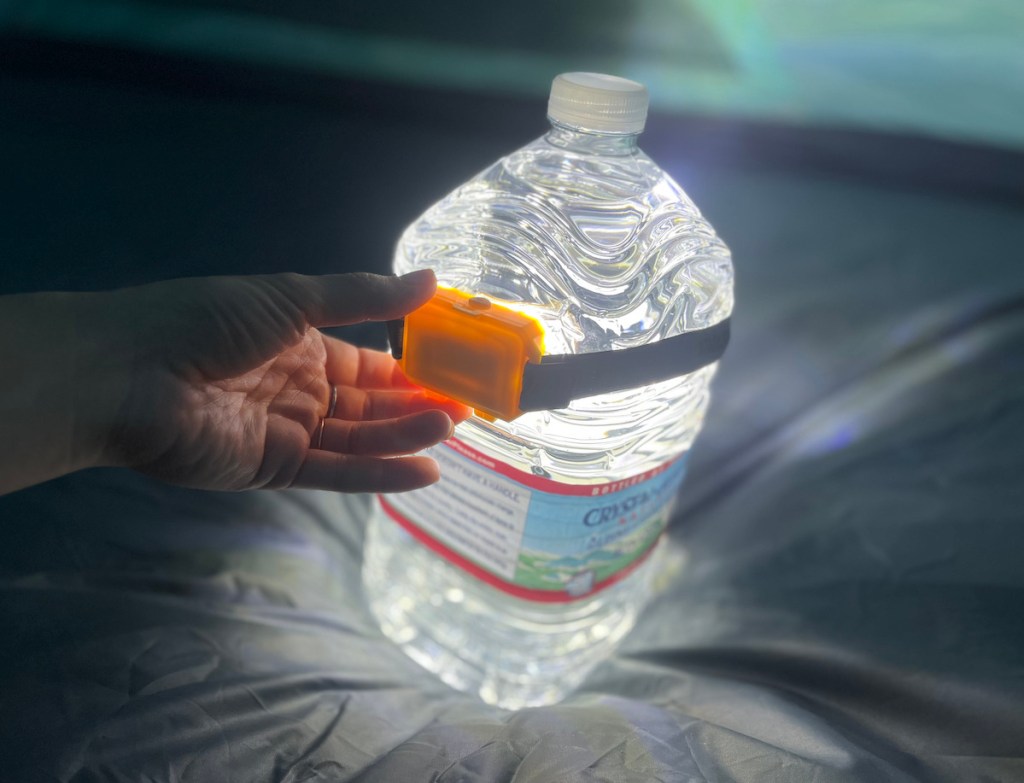 jug of water with headlamp around the body to create camping hacks lantern