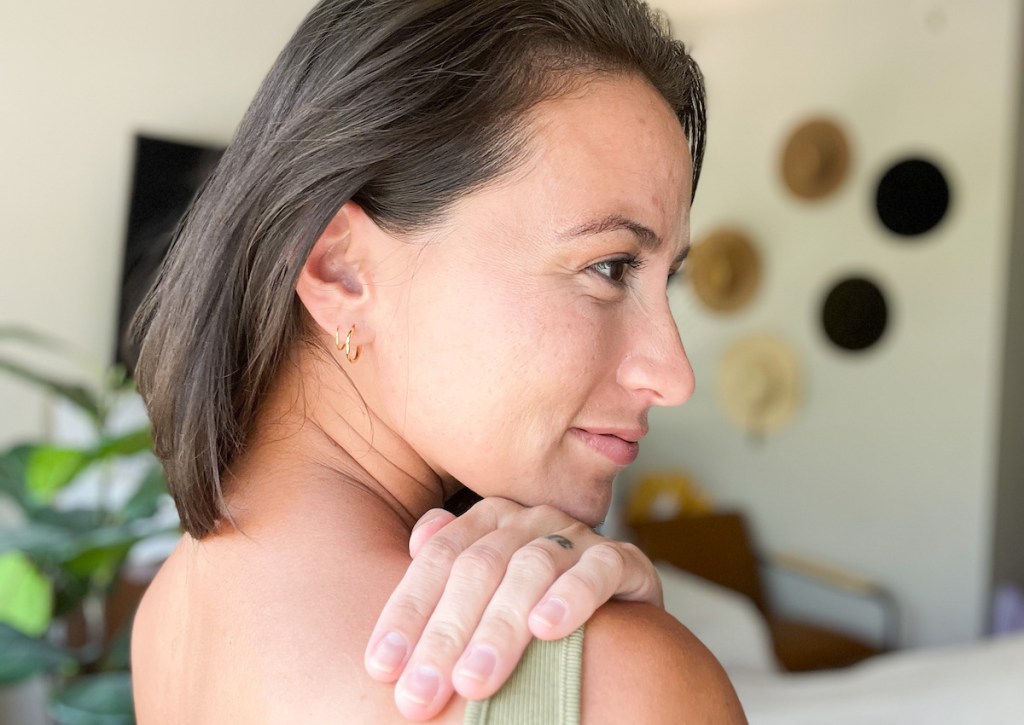 side of womans face with her hand on shoulder showing small hoop earrings