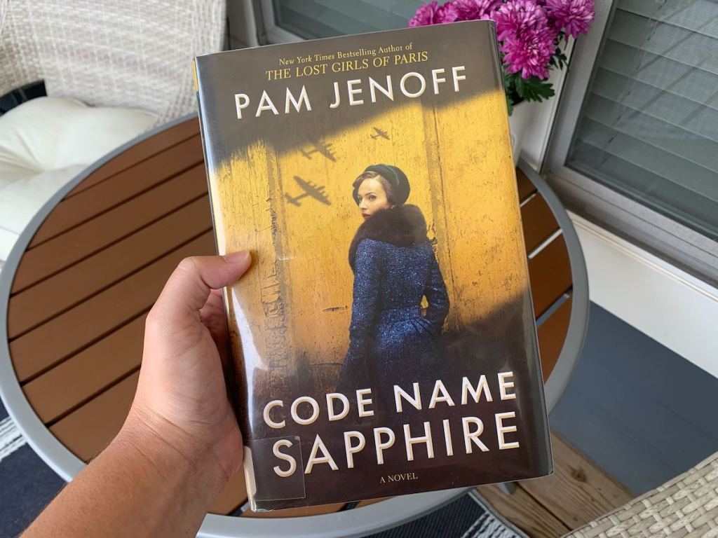 hand holding the book a code name sapphire in outdoor patio
