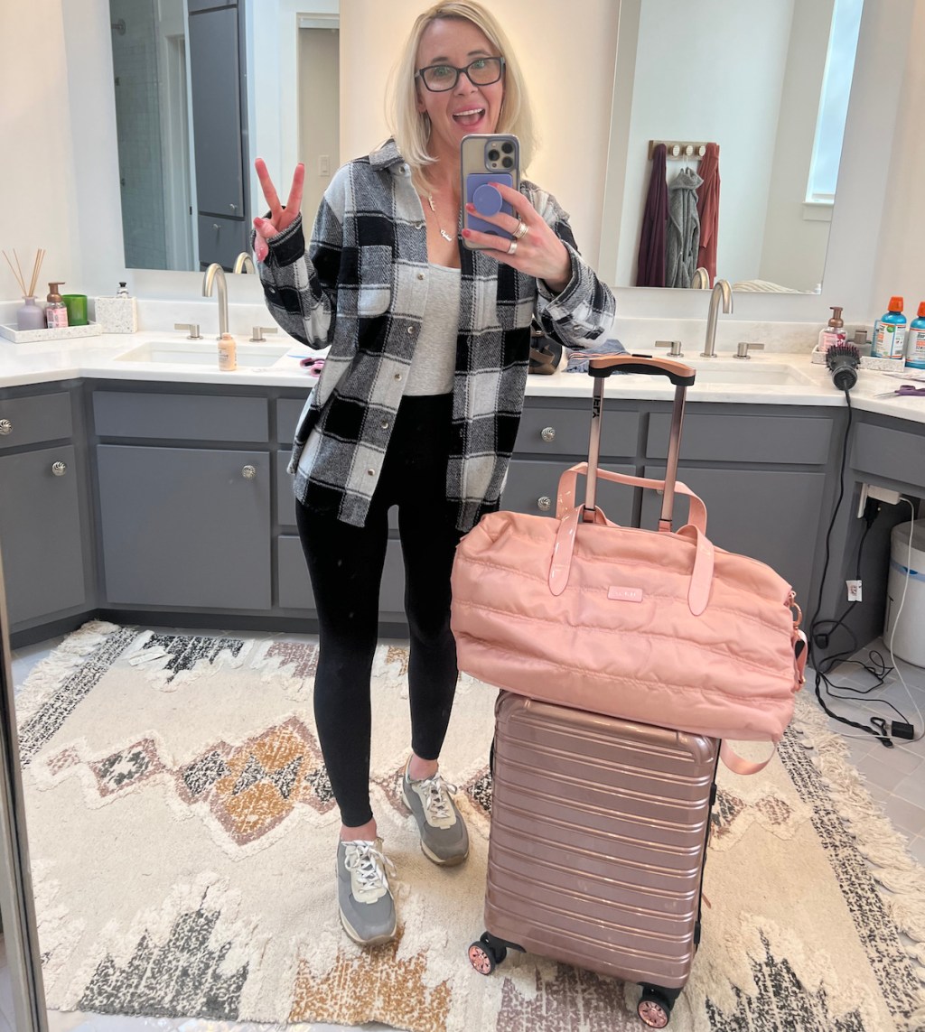 woman taking mirror selfie in bathroom with ifly luggage suitcase