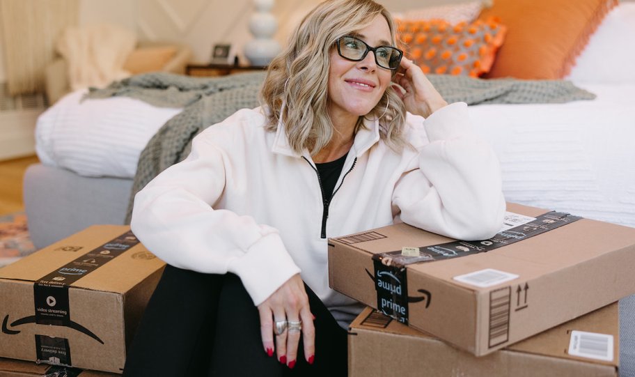 woman sitting on floor in front of bed leaning on amazon boxes