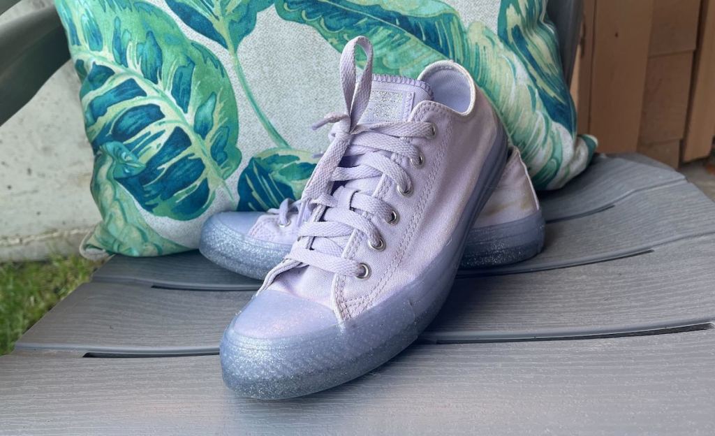 purple converse sneakers on plastic chair with palm tree pillow
