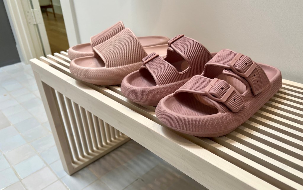 two pairs of pink sandals on slated bench
