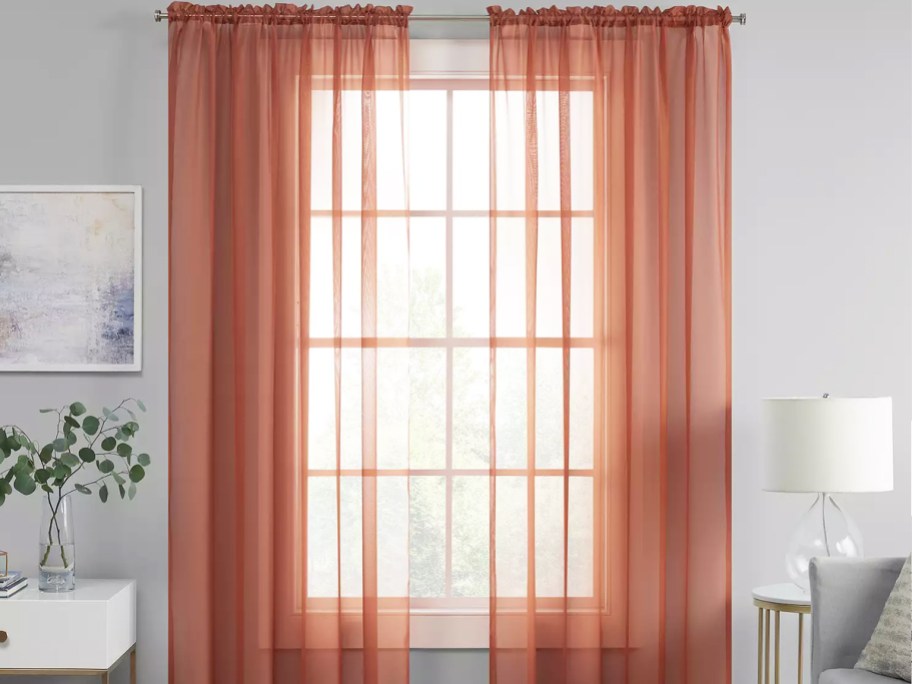 sheer red curtain panels over window