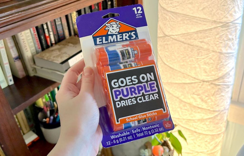 hand holding a pack of elmers purple glue sticks 