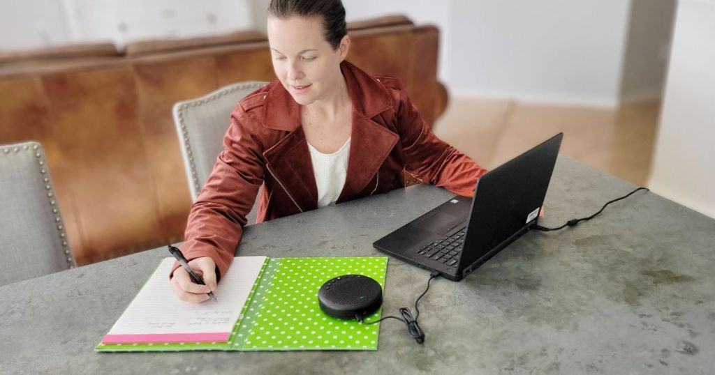 woman working at table with speakerphone connected to laptop in front of her