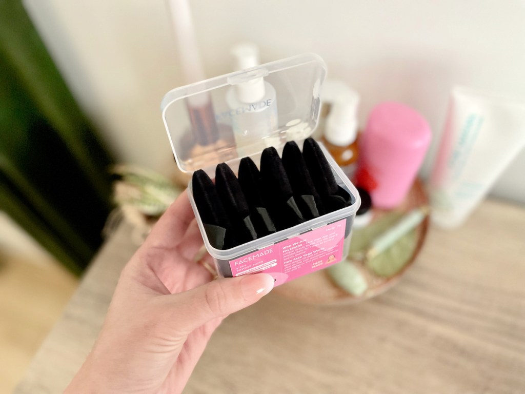 woman holding a case of facemade makeup puffs