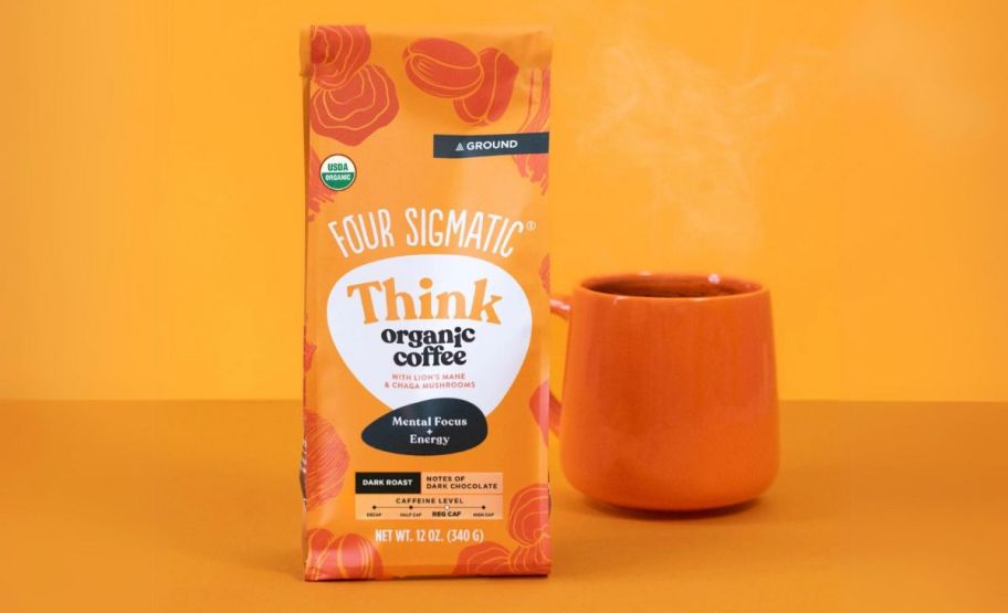 four signmatic coffee bag on orange background next to cup of coffee