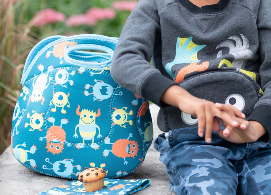 close up of boy sitting next to monster lunch bag