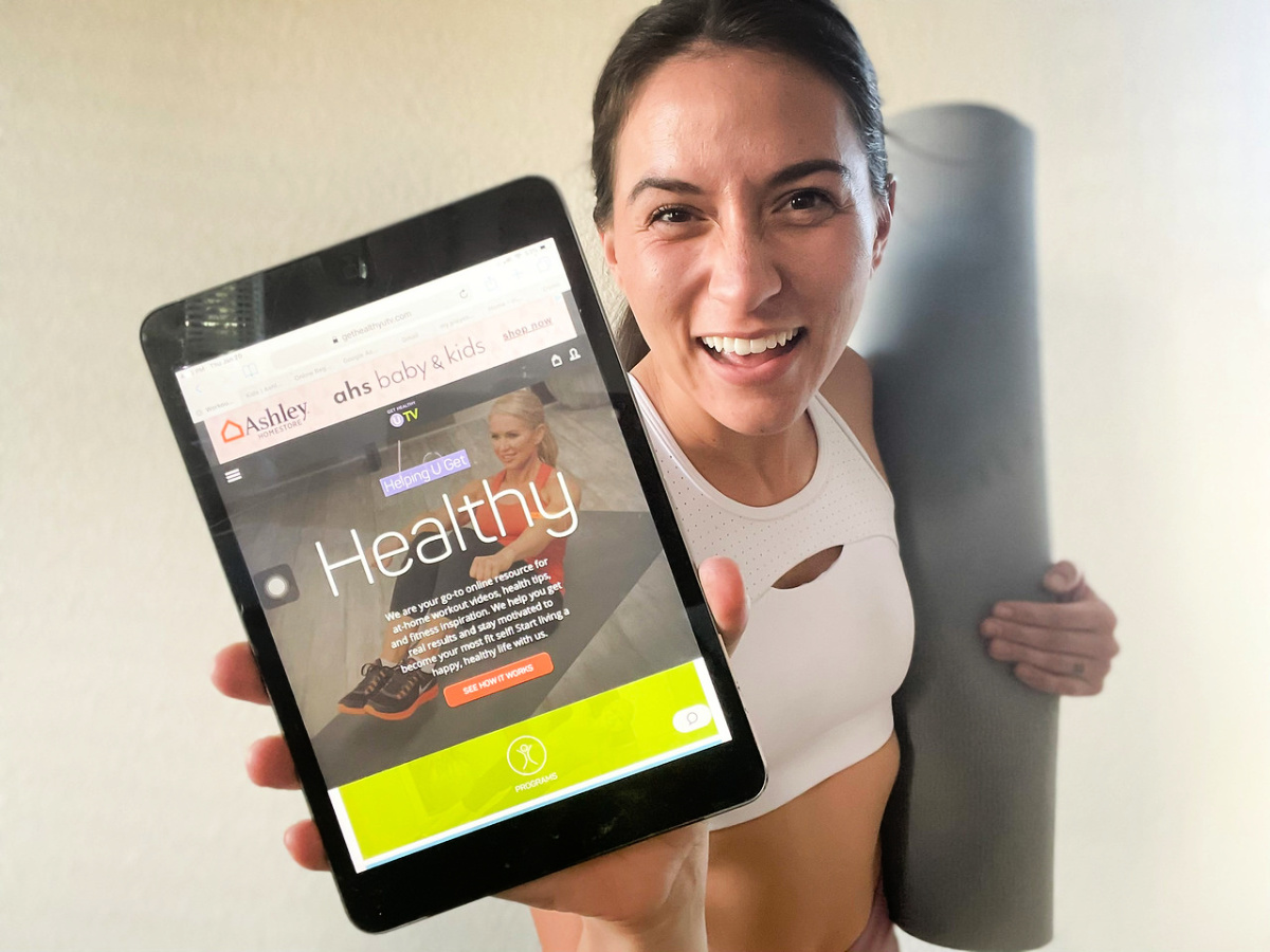 woman showing a tablet with a get healthy u acreenshot