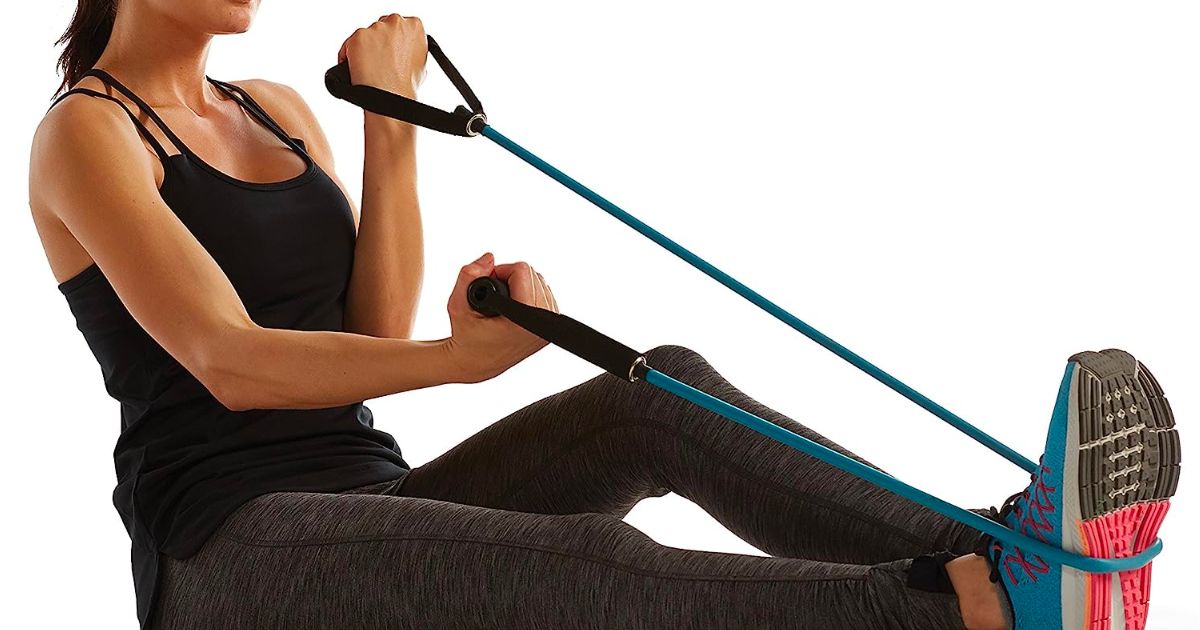 a woman sitting on the floor working out with a gaiam heavy resistance band