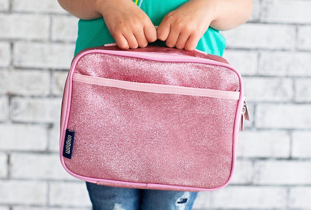 girl holding pink glitter wildkin lunch bags for kids