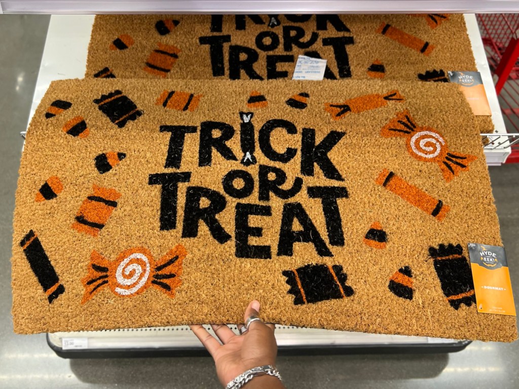 hand holding trick or treat doormat from target