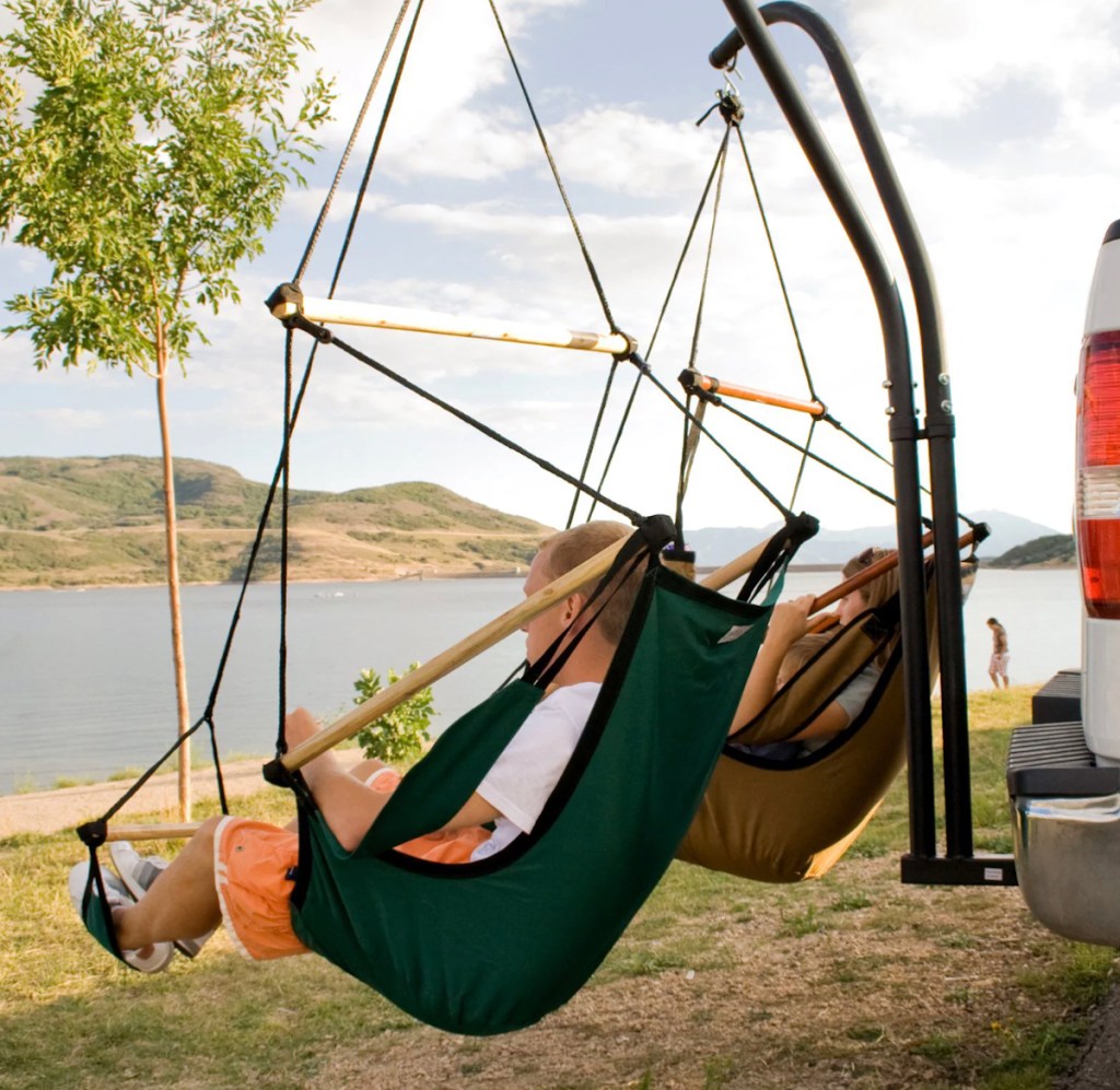 people sitting in hanging hammock chairs hanging from car hitch