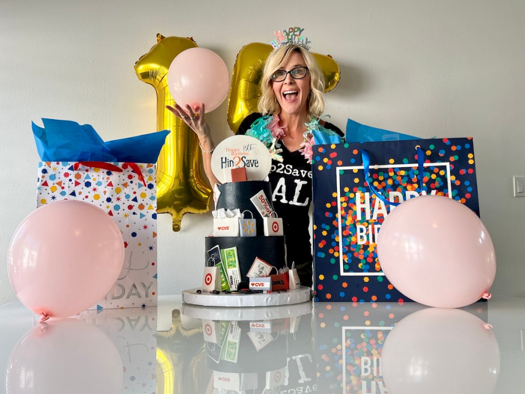 woman holding up pink balloons with birthday cake and presents