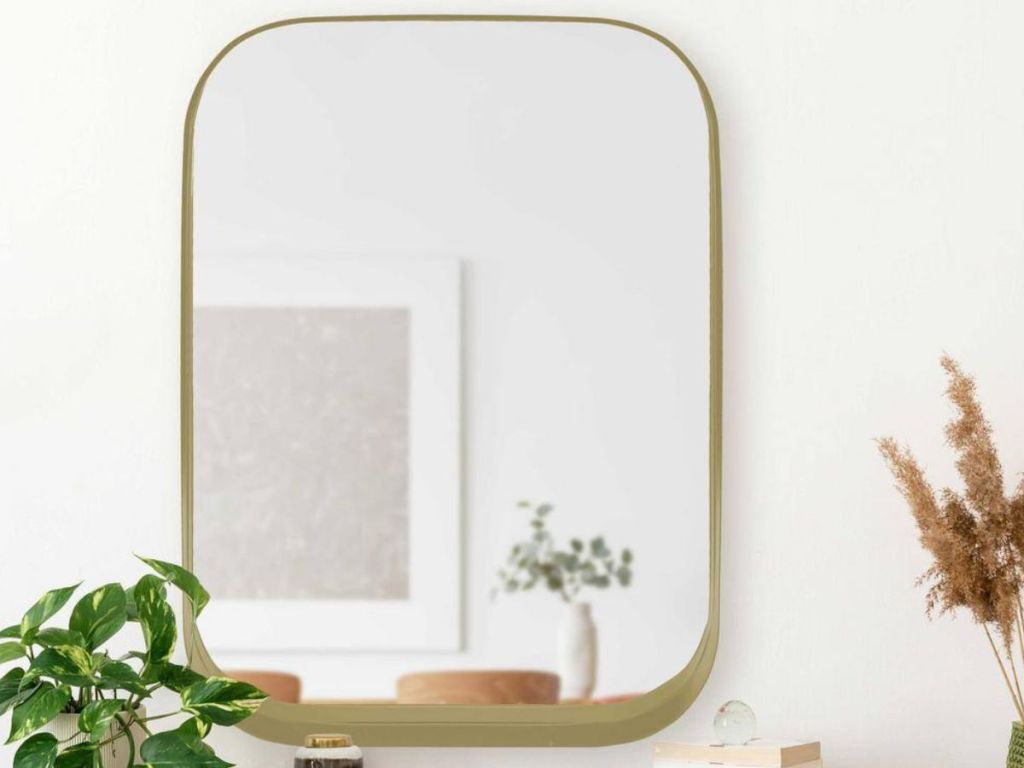 square mirror with gold frame on wall