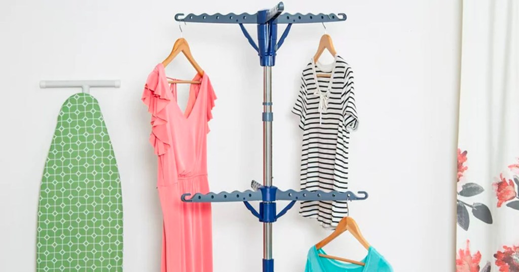 two honey can do tripod racks with clothes hanging on them