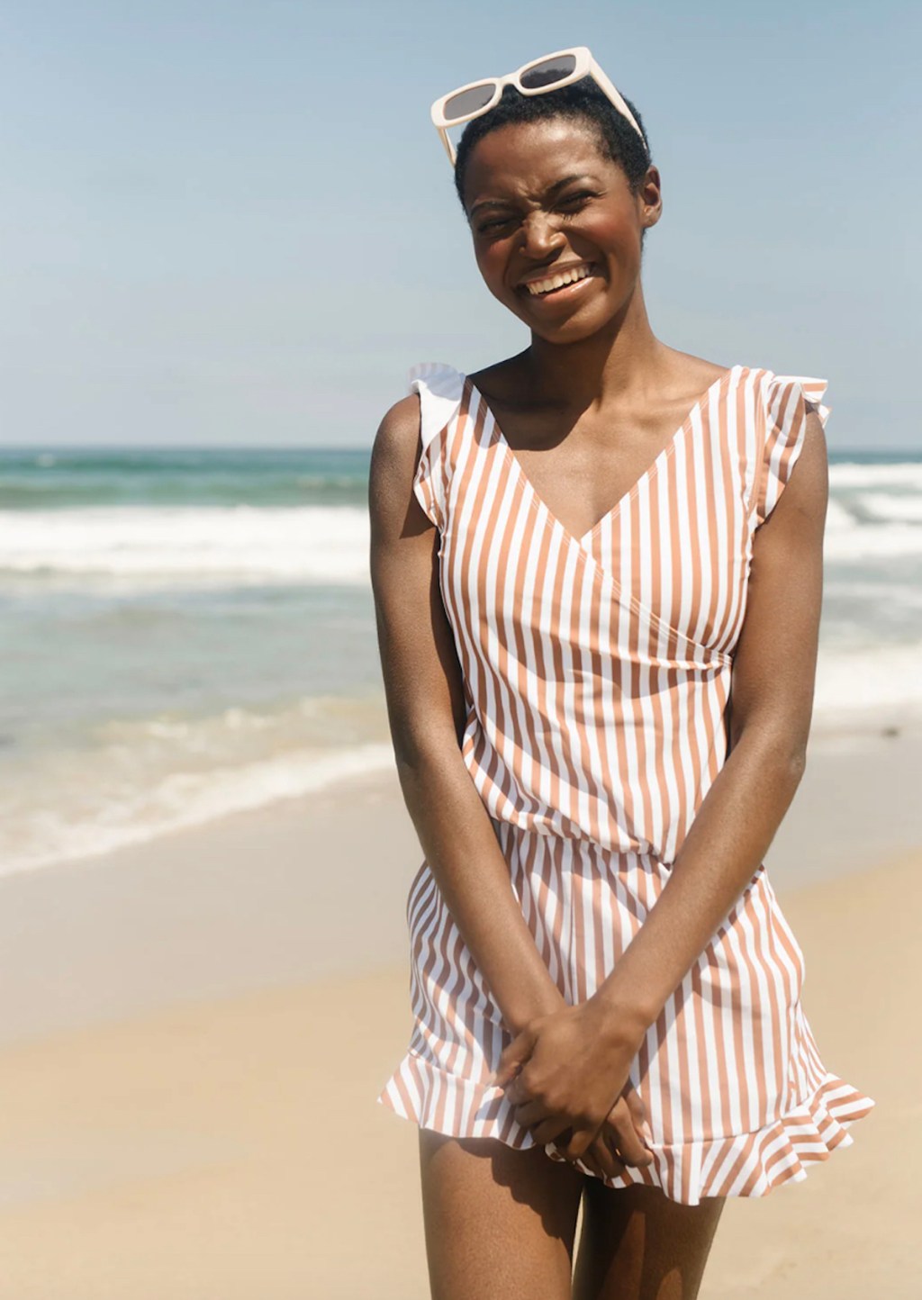 woman standing on beach wearing striped swim romper 