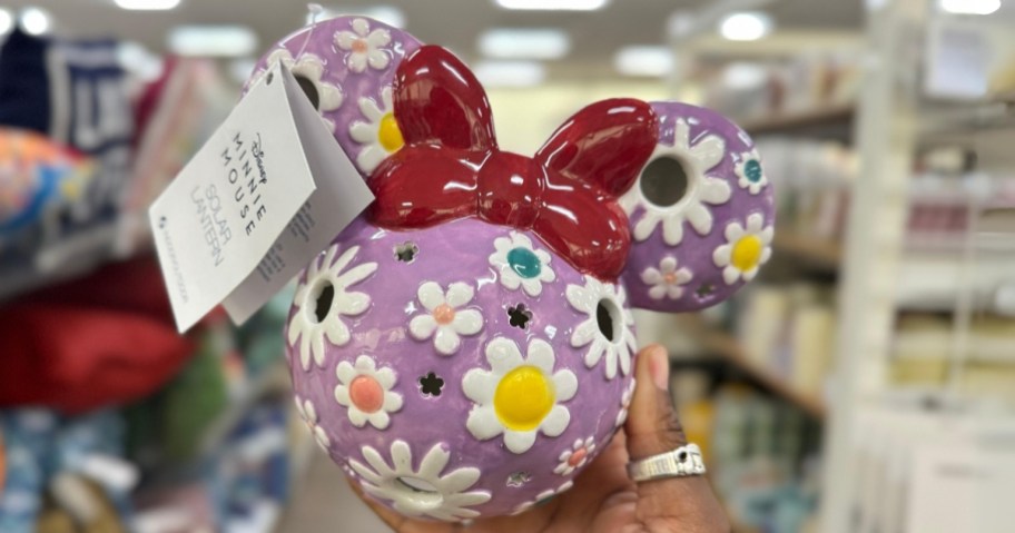 hand holding a Minnie Mouse head shaped ceramic solar lantern in purple with different color flowers on it and red bow
