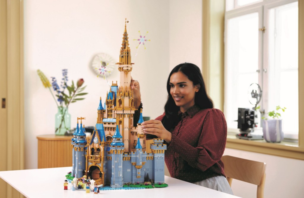 woman putting together the lego disney 100 castle set