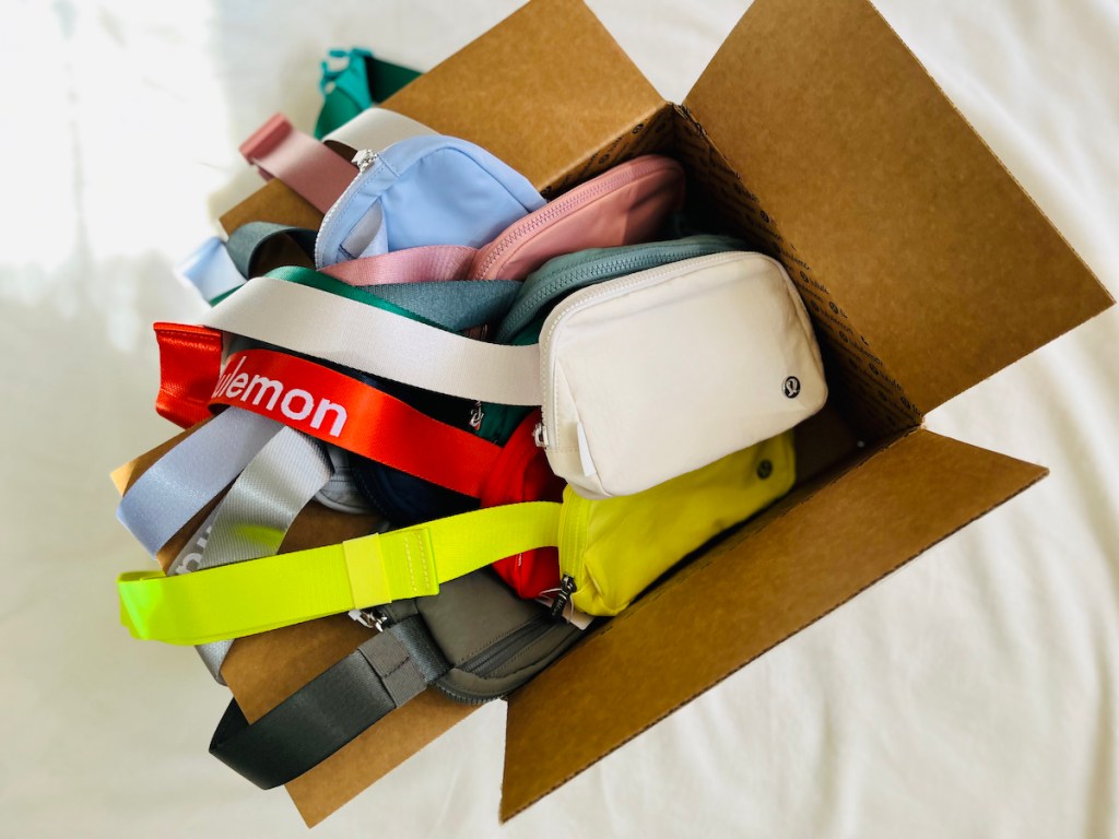 pile of different colored lululemon everywhere belt bags in box on floor