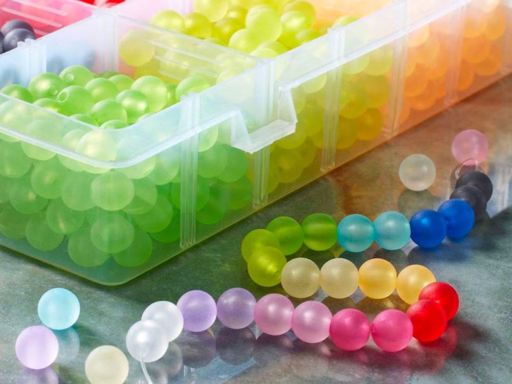colorful beads in plastic box with bracelet laying next to it