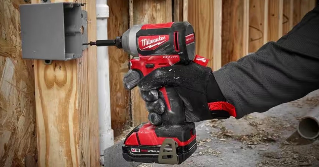 hand using red and black impact driver to screw in box
