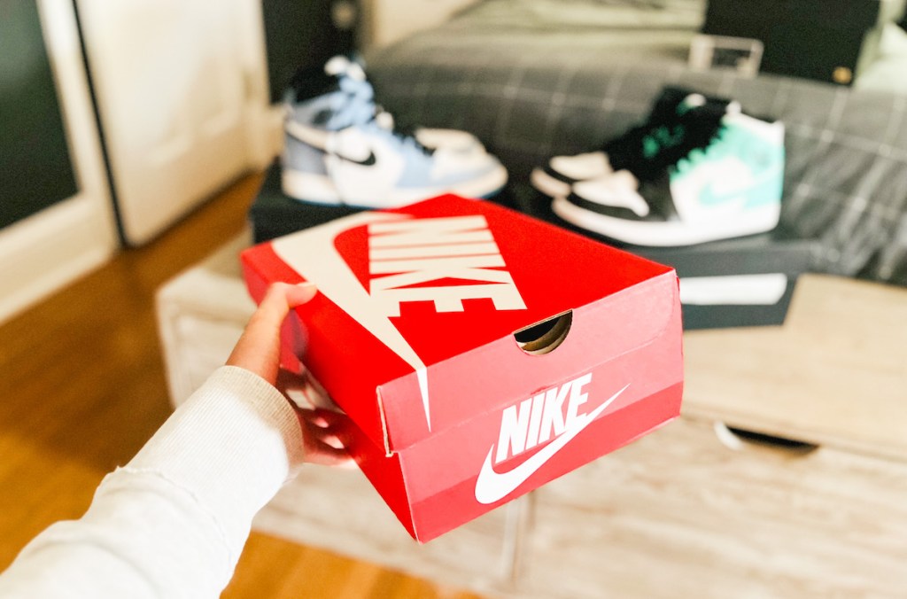 hand holding red nike box in front of air jordan high tops