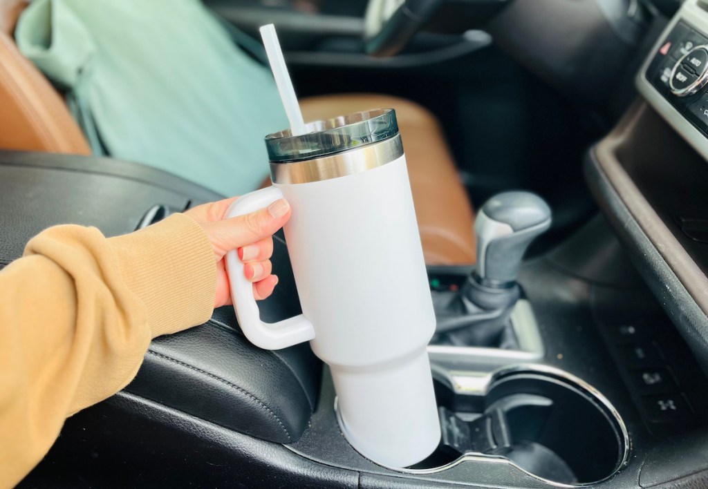 hand holding a white ozark trail tumbler in car cup holder