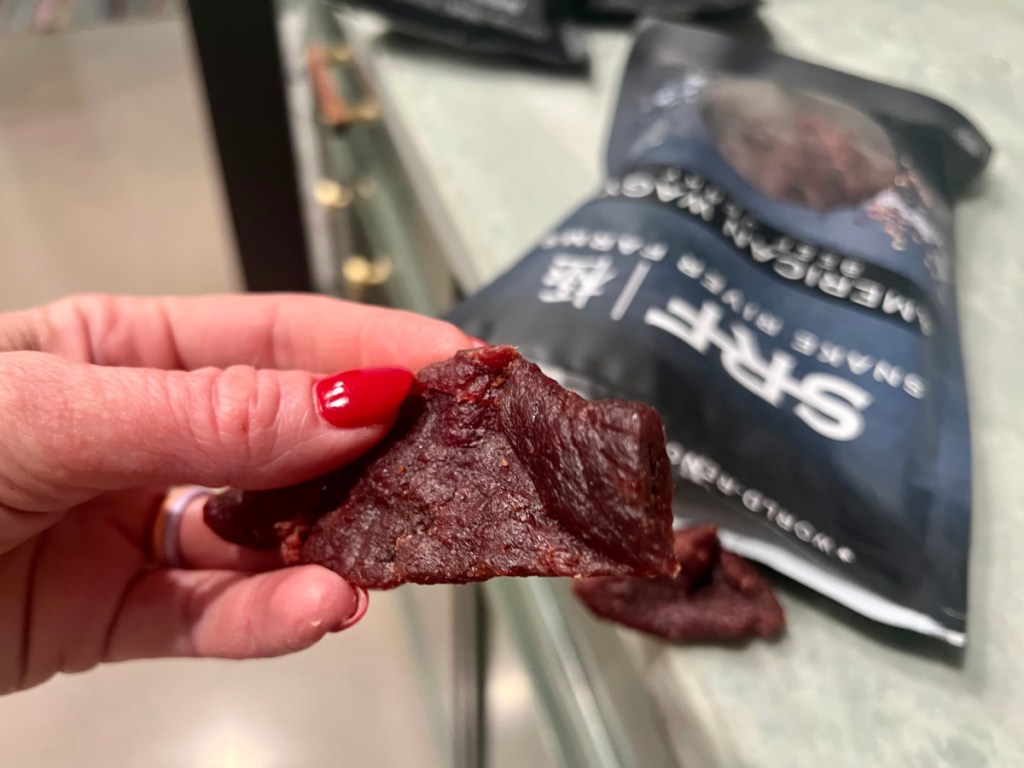 woman with red nail polish holding piece of piece of Snake River Farms Jerky