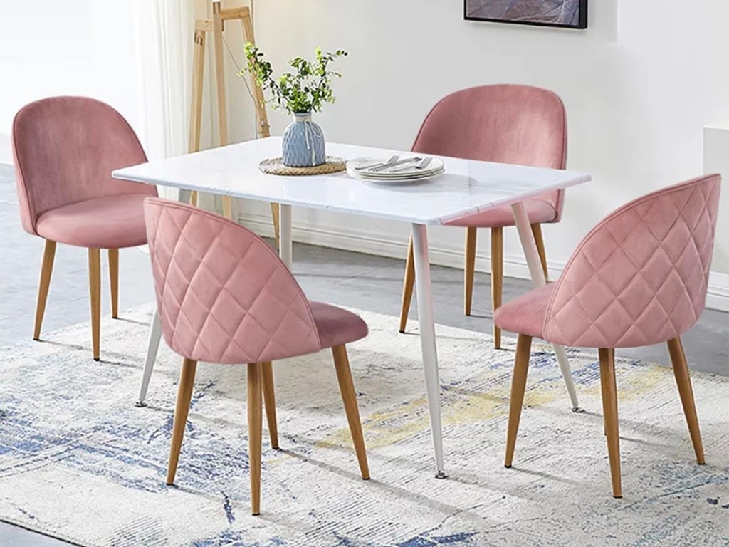 4 pink velvet dining chairs around white dining table