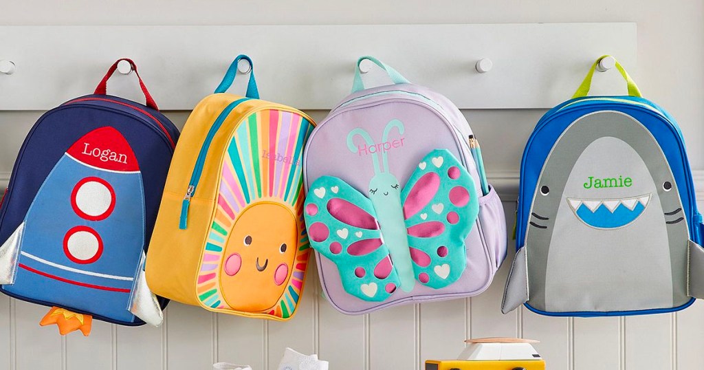 spaceship, sun, butterfly and shark backpacks hanging on rack