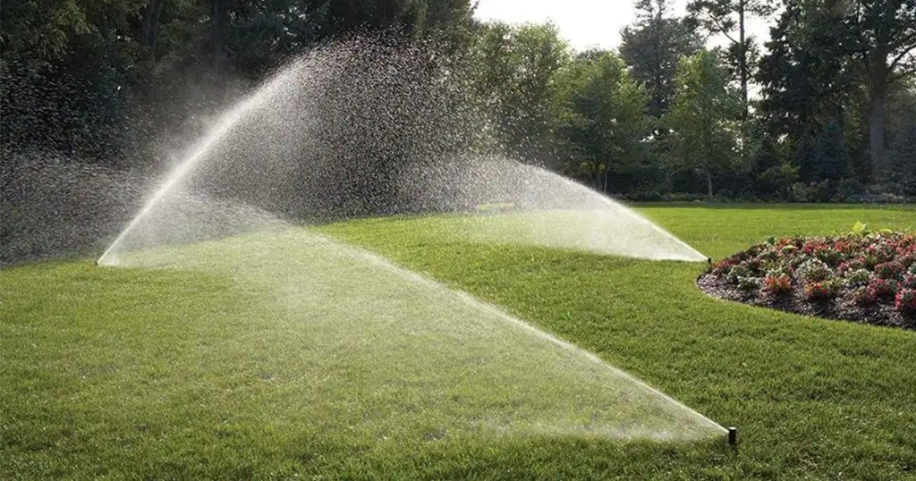 three sprinklers spraying water on grass