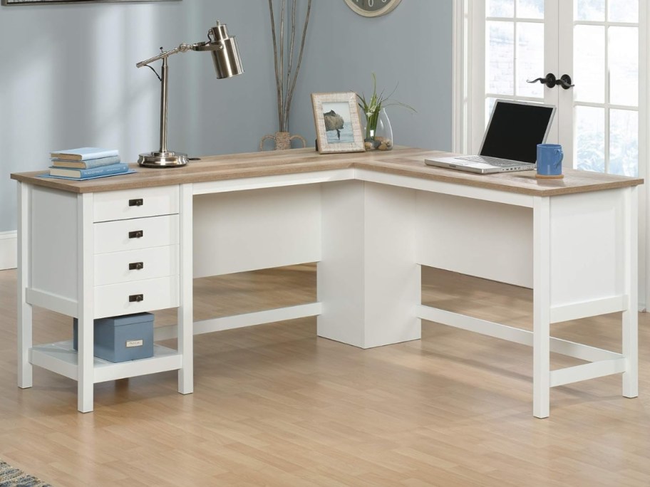 L-shaped desk in white with a light wood top sitting in a room